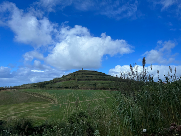 Scenic photo of a bright blue sky over top of green lucious hills